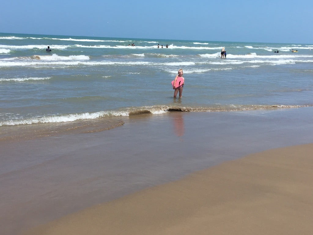 girl standing with boogie board in the ocean in South Padre Texas