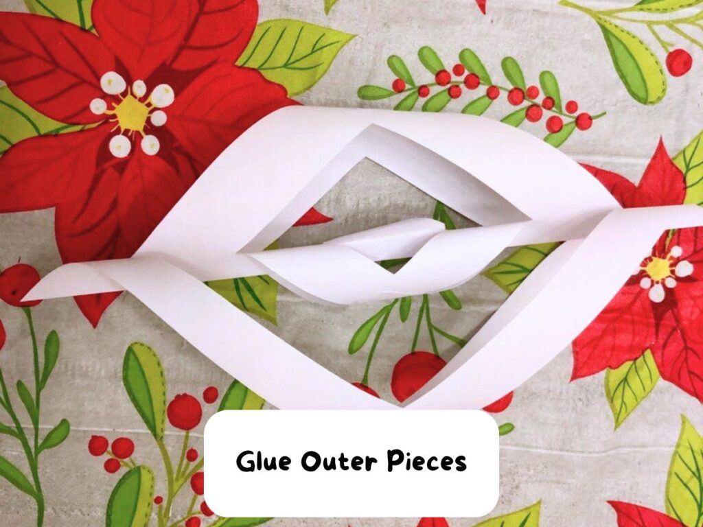 Final white pieces of a cut paper glued together on the outside for the giant snowflake piece. Text: Glue outer pieces