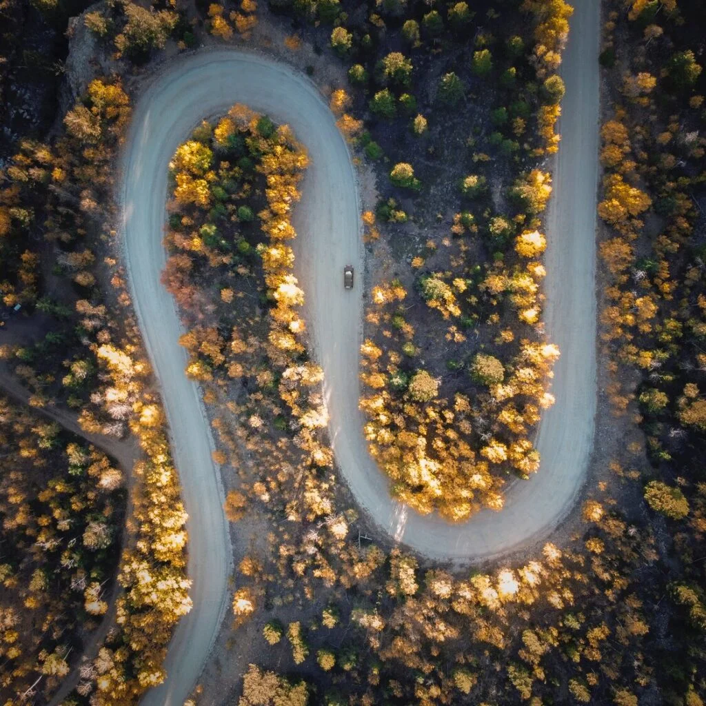 Denver in October provides scenic drives in guanella pass, aerial view of s-curve road through yellow trees