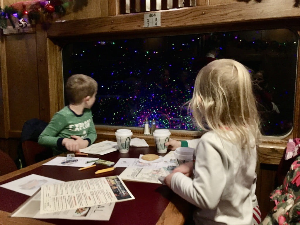 kids looking out a train window at Christmas lights