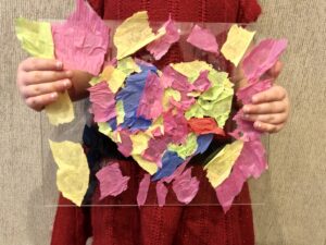 Young child holding a colorful tissue paper heart