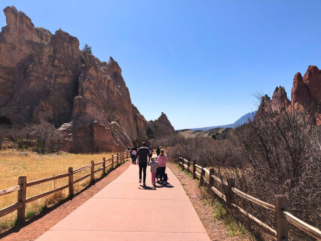 family with a stroller walking on a paved sidewalk at Garden of the Gods