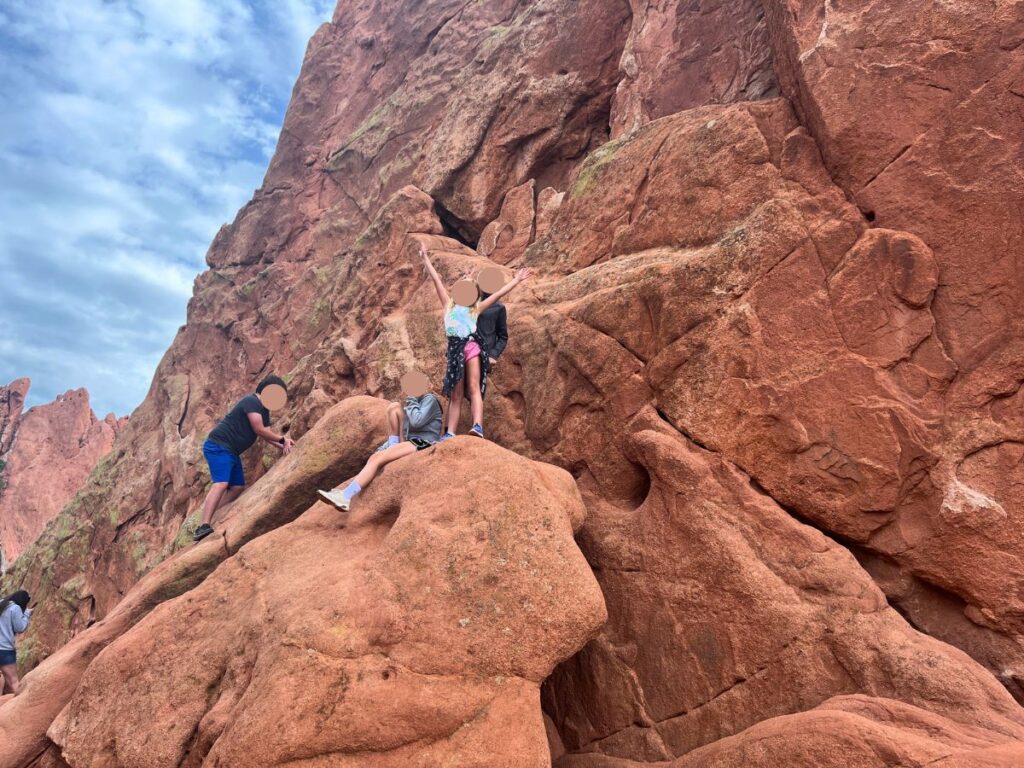 kids that climbed up big red rocks and are standing on top posing at Garden of the Gods