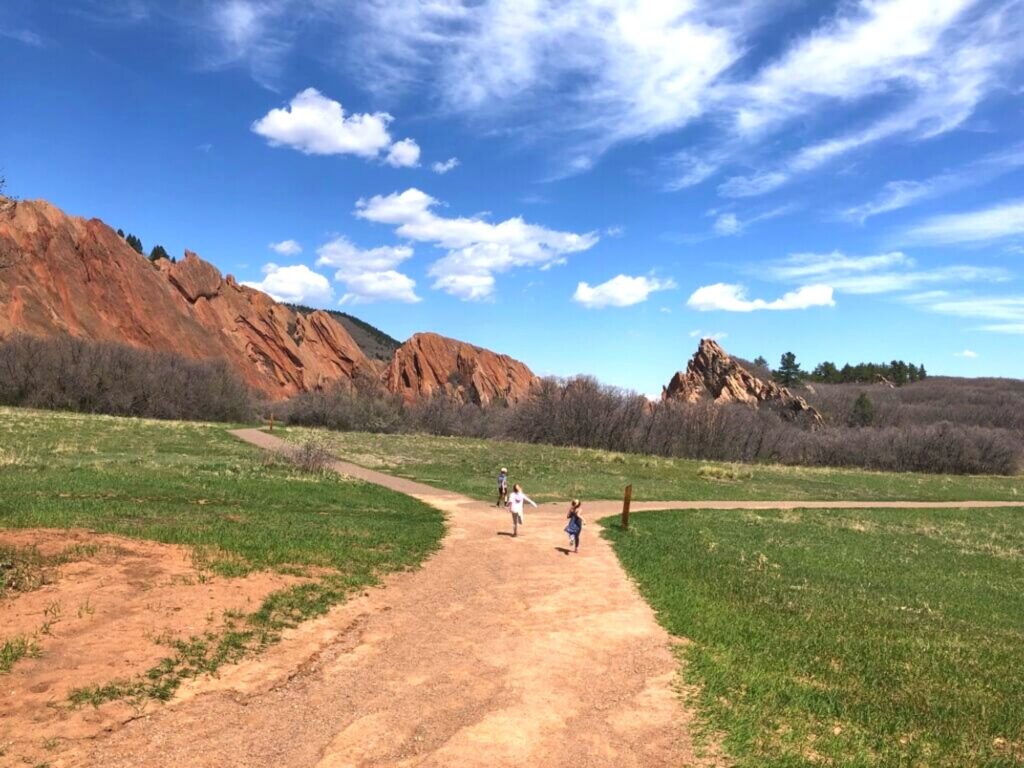 kids running on trail toward red rock formations in Roxborough State Park