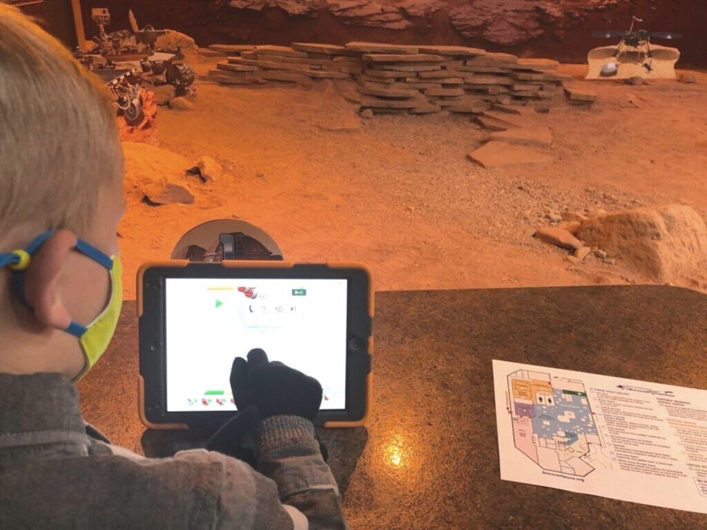 boy playing with a tablet controlling a robot on the red sand and rock in Colorado Springs