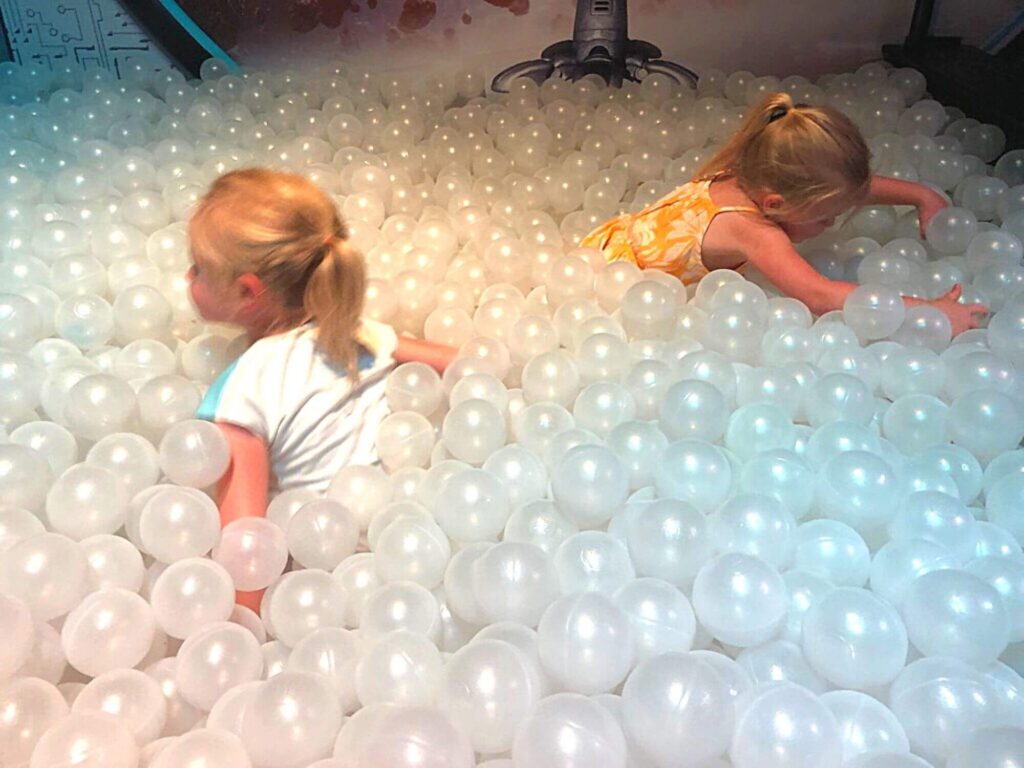two girls playing in a ball pit