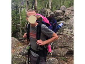 man carrying child in kelty backpack