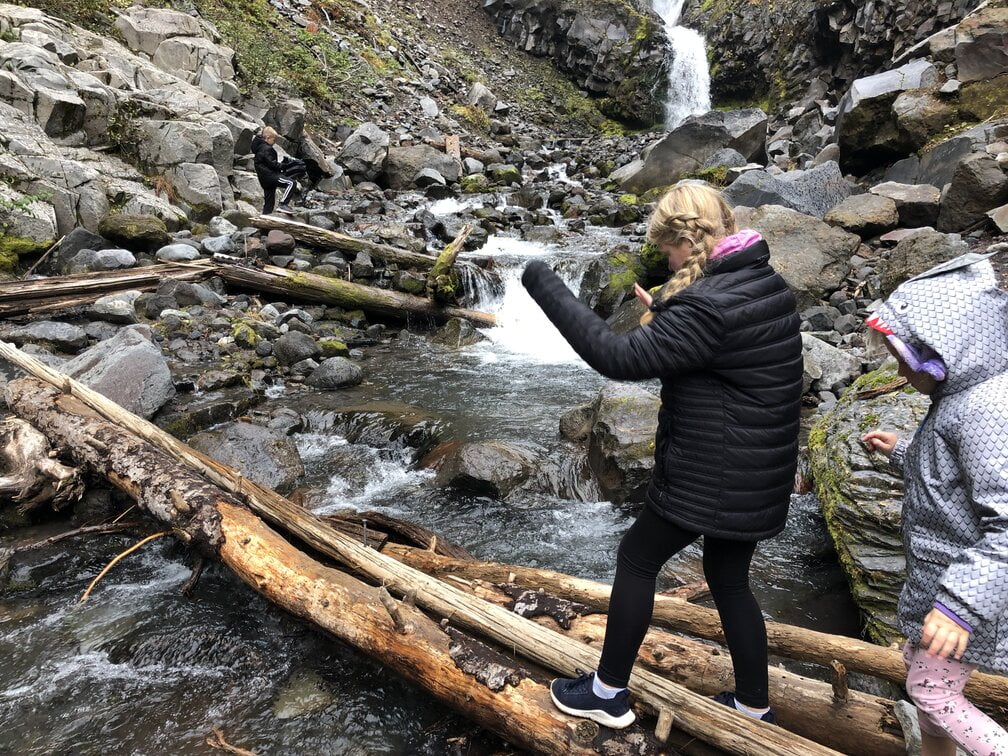 Walking across a log on the river to Comet Falls