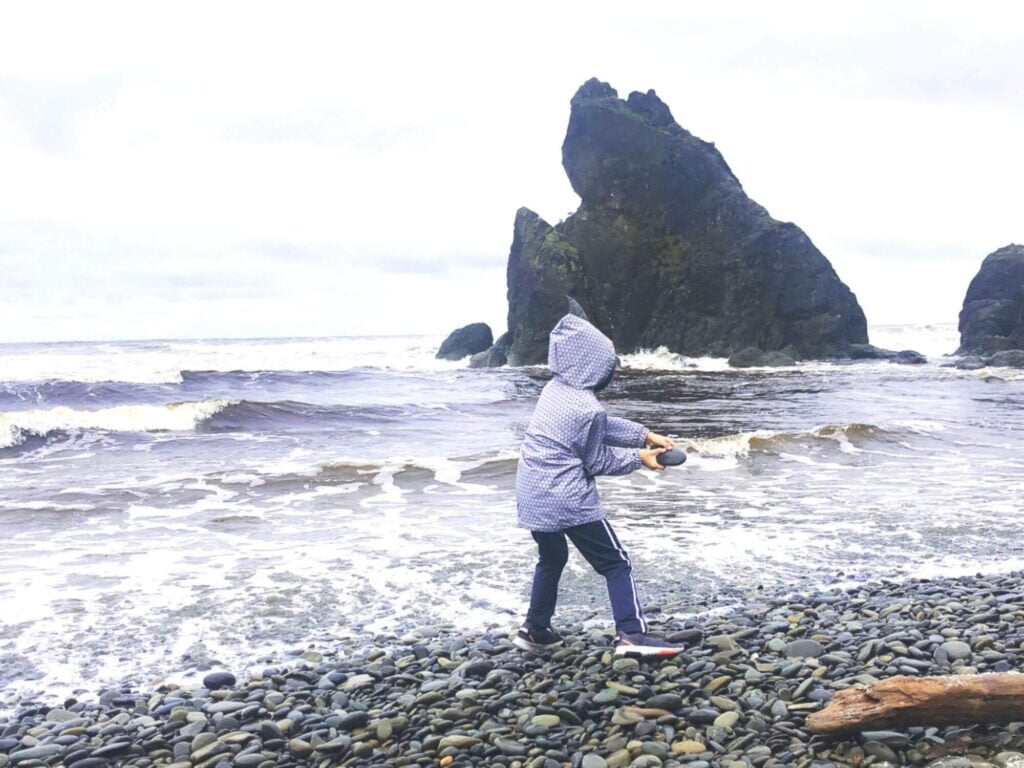 Boy throwing a rock into water at Ruby Beach Olympic National Park