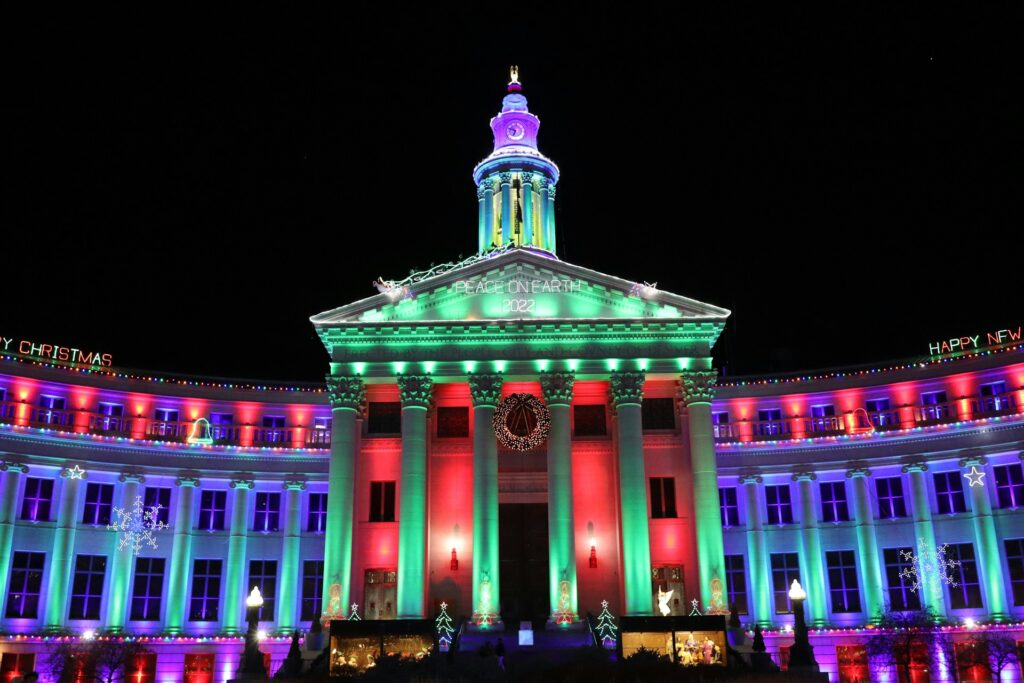 The government buildings in Denver have colored lights shining on them at Light the Lights Denver each year