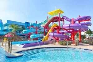 Water Park Hotels in Florida; blue building on left, blue slide on left, orange and yellow slide in middle, purple swirly slide on right
