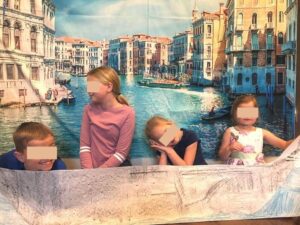 4 kids on a DIY gondola with Venice tapestry in back