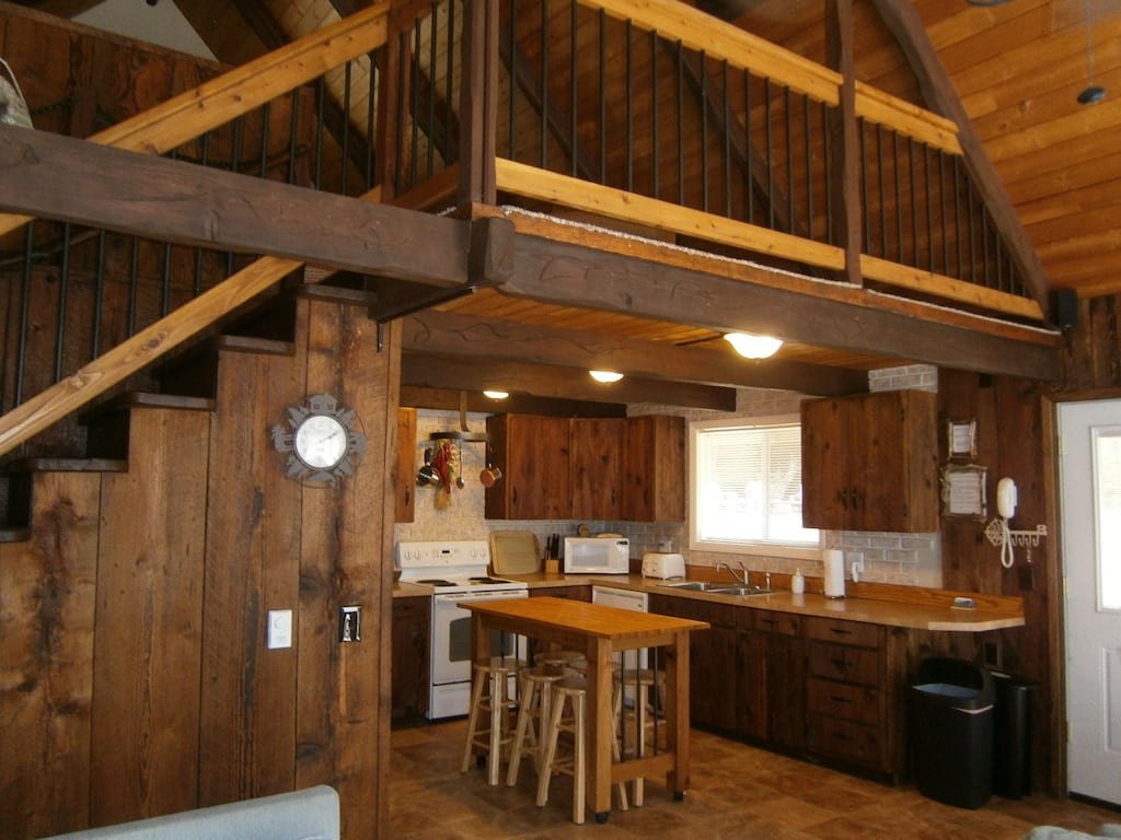 Indoor kitchen mostly made of wood with small view of upper floor railings
