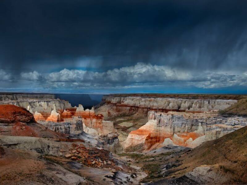striped sandstone formations at Coal Mine Canyon with ominous clouds above