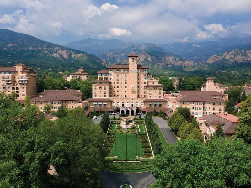 giant pink resort with manicured green grounds, mountains in the background