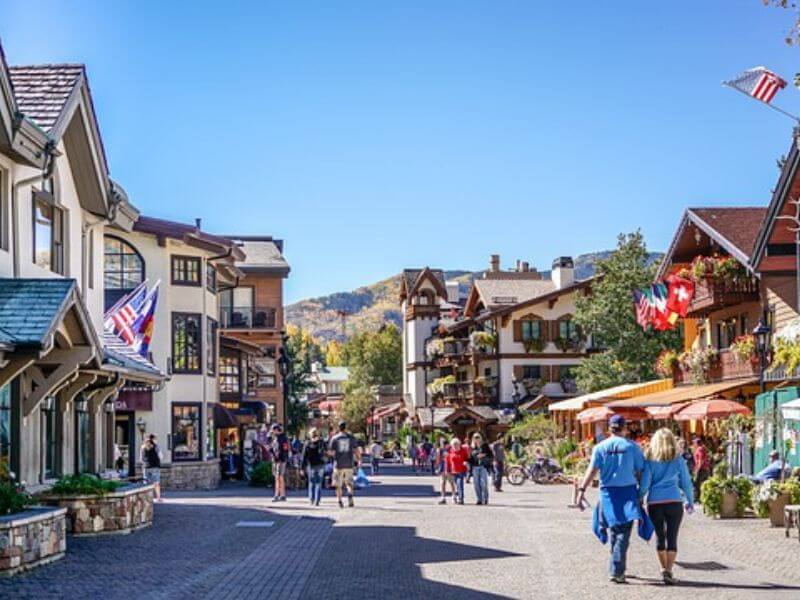 people walking through wide road with swiss-inspired buildings on the side in Vail