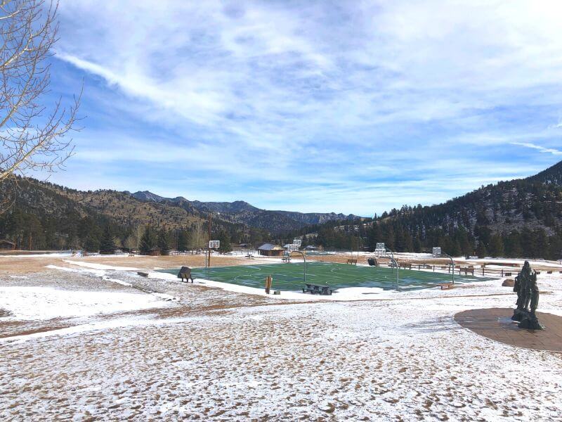 snow covered ground and green-top basketball court in the distance at YMCA of the rockies estes park