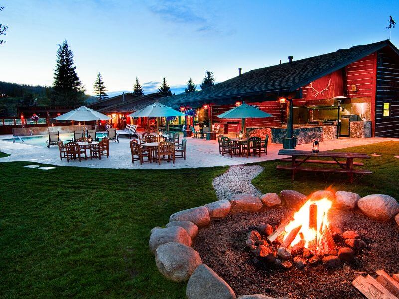 outdoor at dusk, campfire, tables, lodge to the right, pool in background at C Lazy U Ranch