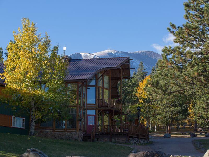 large brown lodge with fall color trees in front