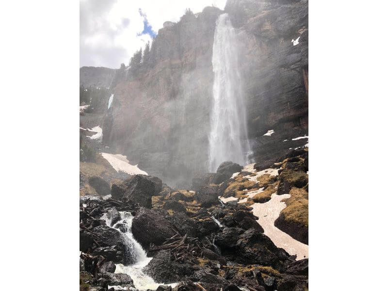 tall waterfall coming down a mountain with lots of mist spraying off