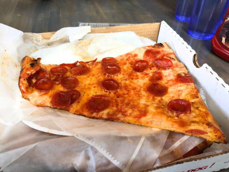 large slice of pizza in a small pizza box