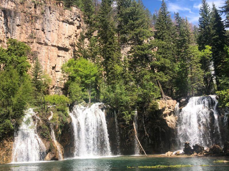 Hanging Lake, three waterfalls dropping into green waters with a tall rock cliff behind