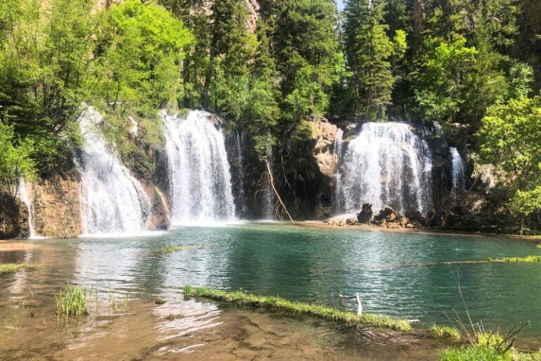 three waterfalls dropping into a green water lake