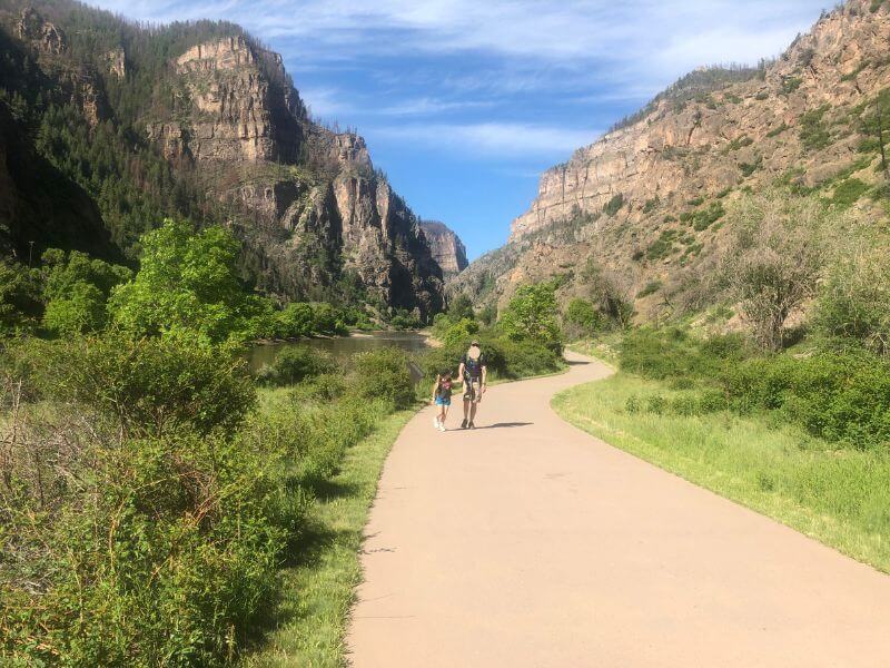 man and child walking on a sidewalk in a canyon