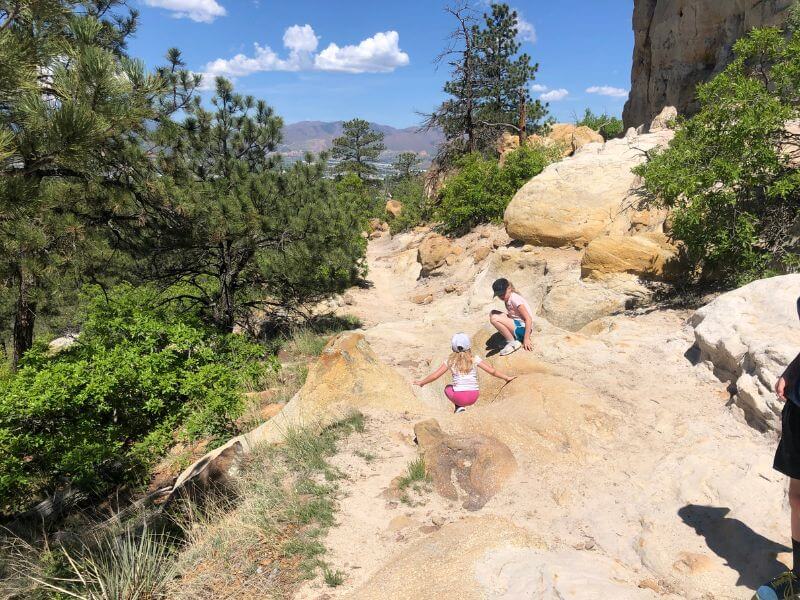 two kids climbing down a smooth bumpy rock trail