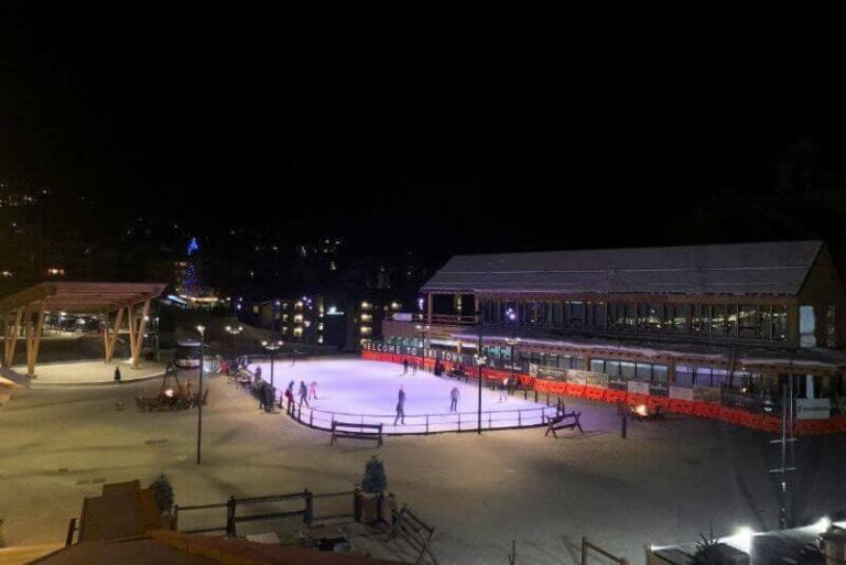 ice rink glowing in the night time in a ski village