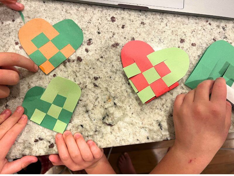 kids hands creating woven hearts out of colored paper