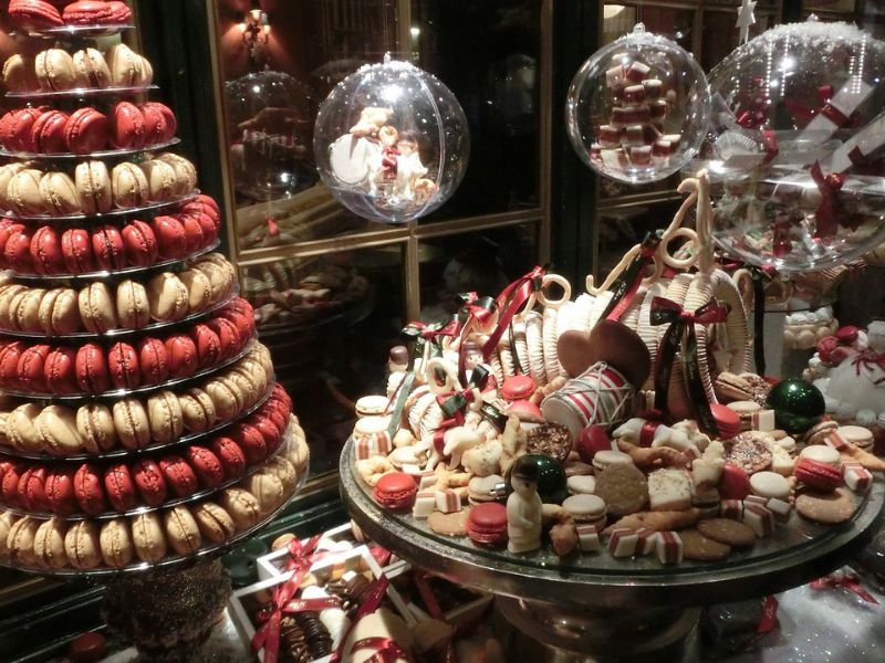 a counter with a beautiful display of macarons in white and red, plus a dish of other confections