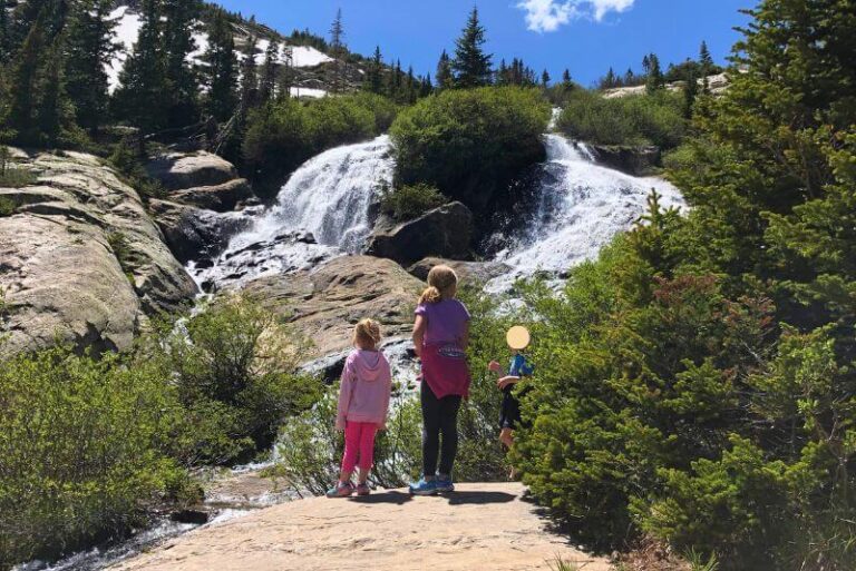 Waterfalls near Breckenridge include McCullough Gulch, a waterfall split into two by a large bush. Kids standing in front staring at it