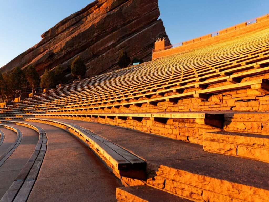 large amphitheater with red rock wall in distance at sunrise (warm glow)