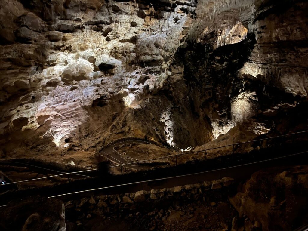 inside a dark cave, just a little light shows on the rock ceiling above and on the path that winds below