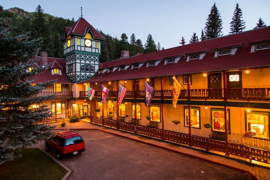 The exterior of the Redstone Inn at dusk when the outside lights are illuminated. A long, 2 story hotel with a tower in the corner.