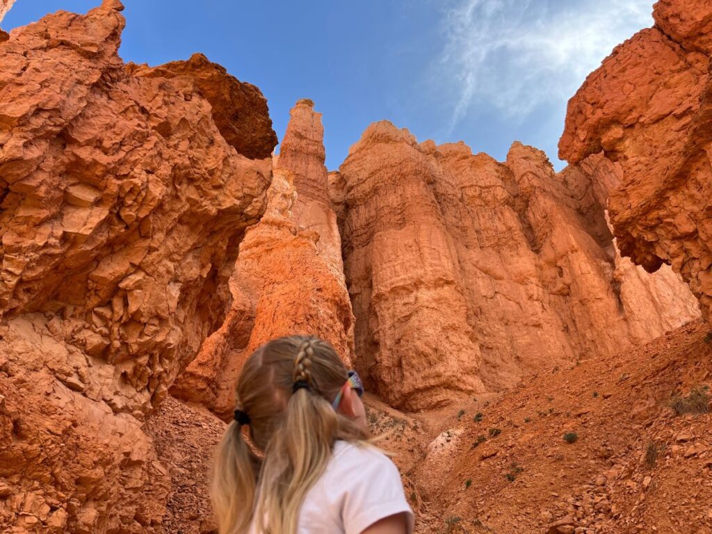 backside of a little girl looking up at tall red rock walls