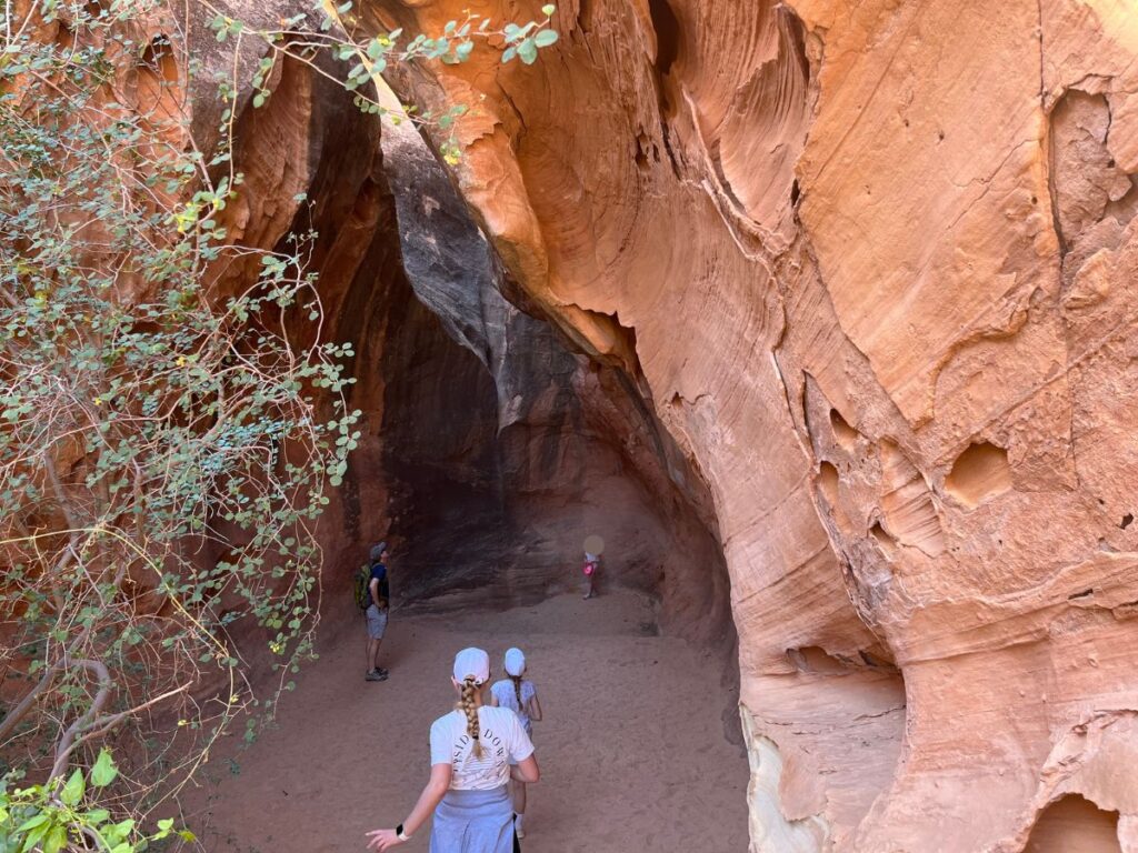 young kids heading into a narrow sandy path netween two red rock canyon walls at Capitol Reef National Park