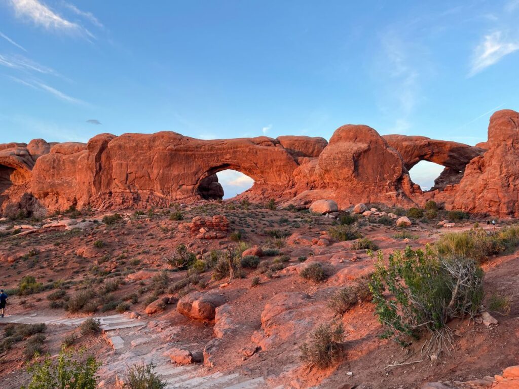 a deep golden hue hits the red rock of Windows arches in Arches National Park at sunset