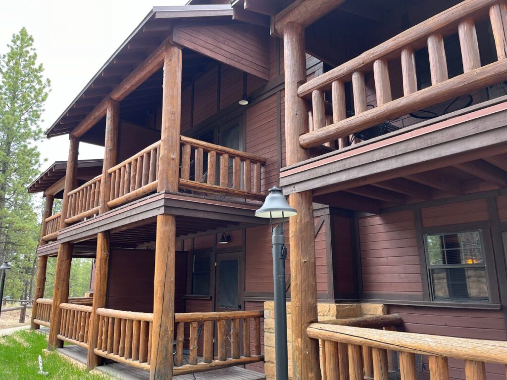 close up of a dark brown wooden hotel with thick log rails as the balcony. The Bryce Canyon Lodge