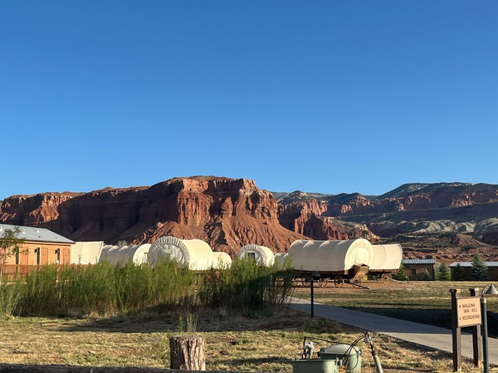 covered wagon area is where you can stay at Capitol Reef resort. Red rock forms in the distance behind
