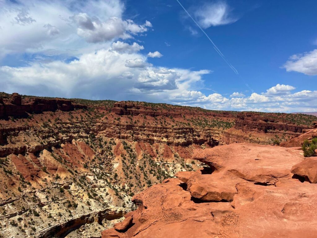 overlook at Goosenecks trail at Capitol Reef. Red rocks in the foreground and a scenic red ridge that turns white on the bottom half in the distance