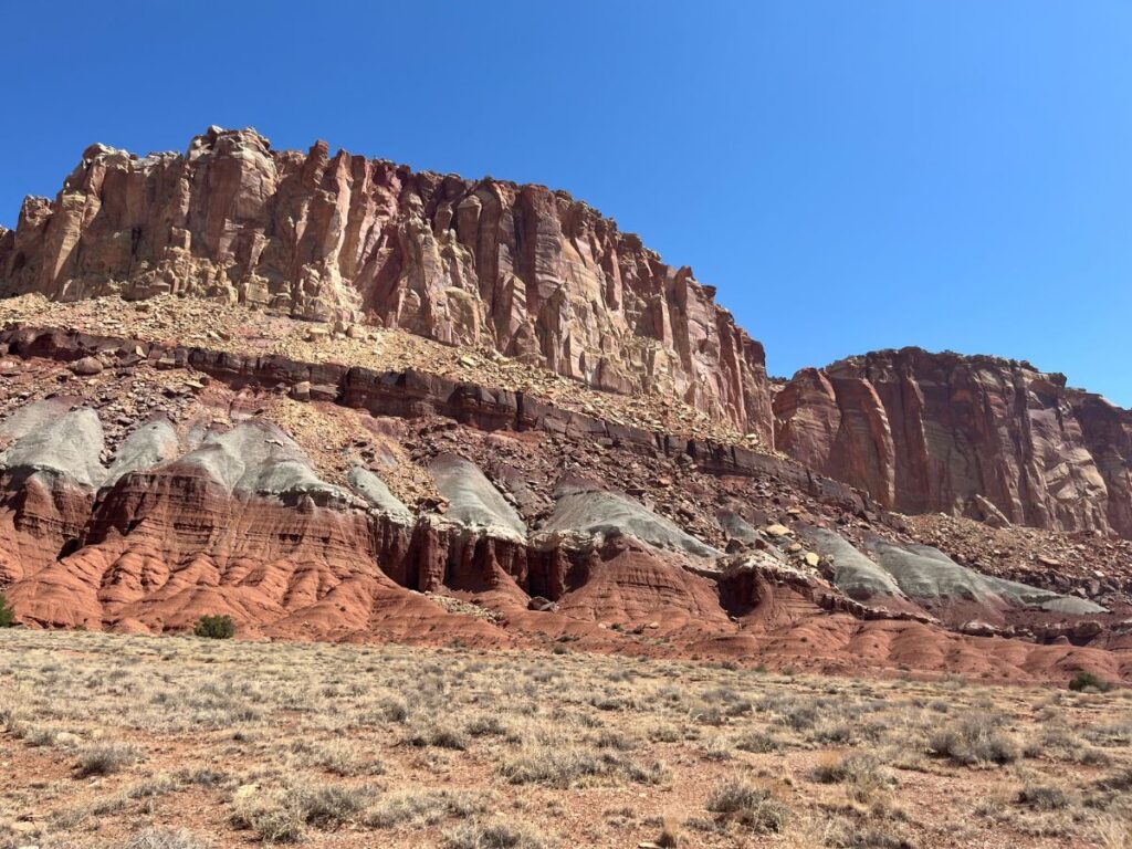 the scenic drive at Capitol reef gives you great views, like tall red rock walls that turn white and different shades, triangle shaped features on bottom