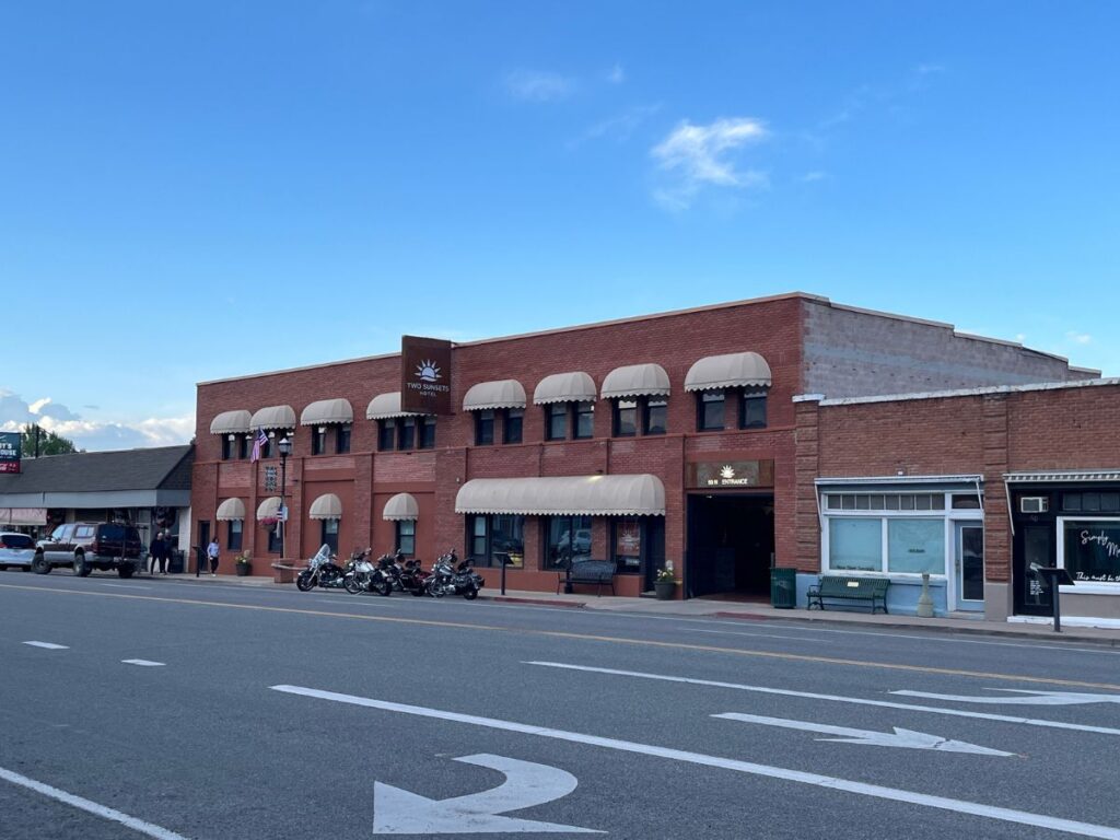 looking across a road at Two Sunsets Hotel in Panguitch, Utah. A two story brick building