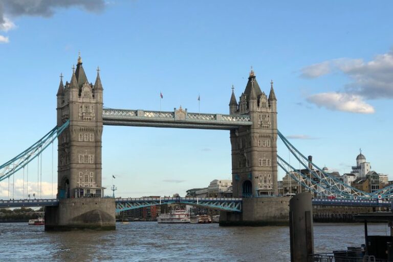 Tower Bridge in London. Two tall skinny tower spires with a foot bridge going across the top. It sits over a river