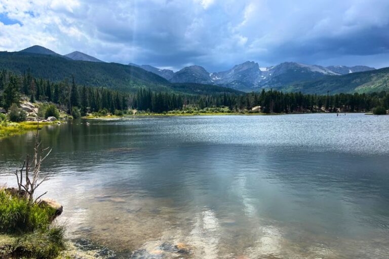Dark skies overhead with a mountain backdrop to Sprague Lake in Rocky Mountain National Park