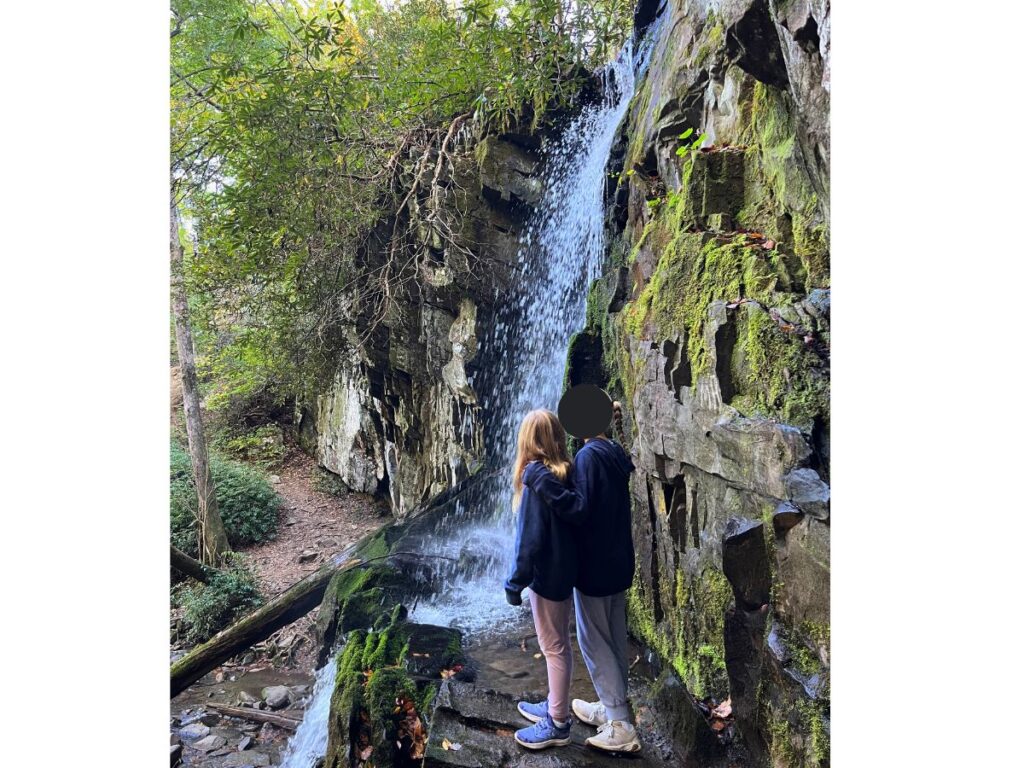 Baskins Creek Falls in Great Smoky Mountains National Park. A view from up higher, eye level with the falls, and two girls standing nearby in front