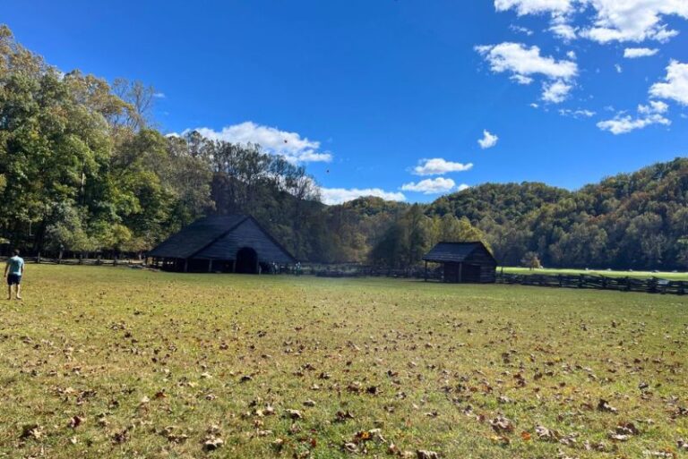 Mountain Farm Museum is a great stop if you have 1 day in Great Smoky Mountains National Park. A flat, grassy area with two historic cabin-like structures in the distance
