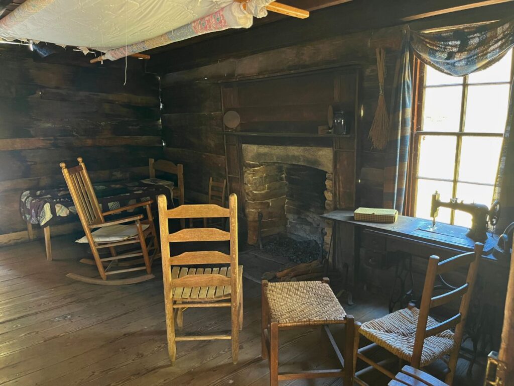 inside an old farmhouse in Great Smoky Mountain National Park at the Mountain Farm museum. Old wooden rocking chairs face a stone fireplace