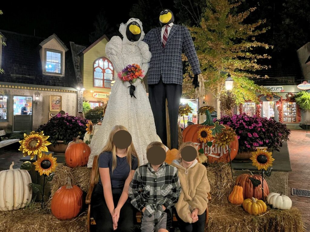 Fall in Gatlinburg brings lots of decorations.  Human-sized birds in a wedding dress and suit, surrounded by hay bales and pumpkins with 3 kids sitting in front.